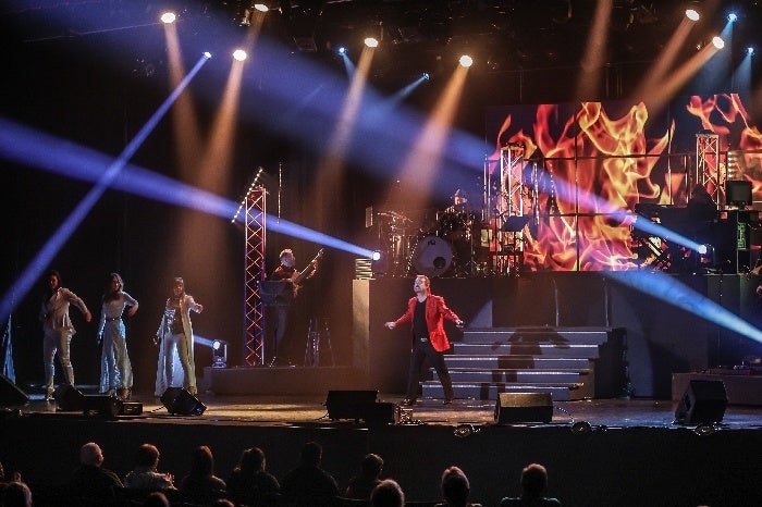 Performers on a brightly lit Branson variety show stage in front of an audience